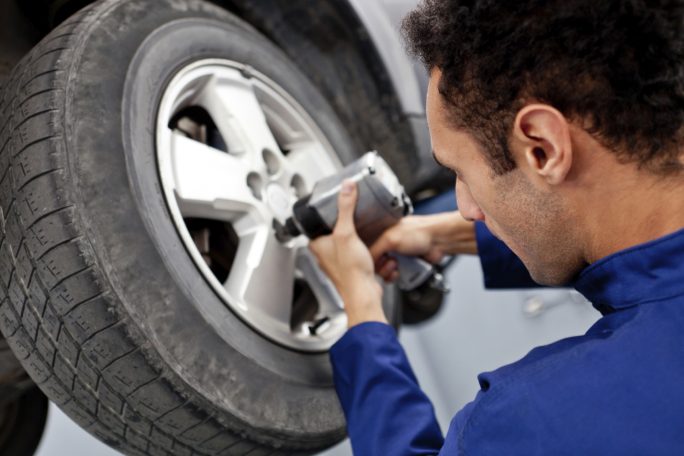 A mechanic using a power tool to remove a wheel from a vehicle. repair car repair, repairs on cars. Garages in Coventry. Battery charging