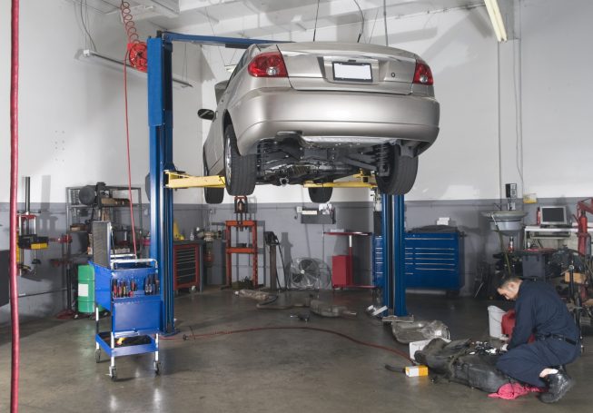 A car elevated on a lift in a workshop. Vehicle mechanic near me, serviced near by me, garage car garage, garage near by me. Engine oil